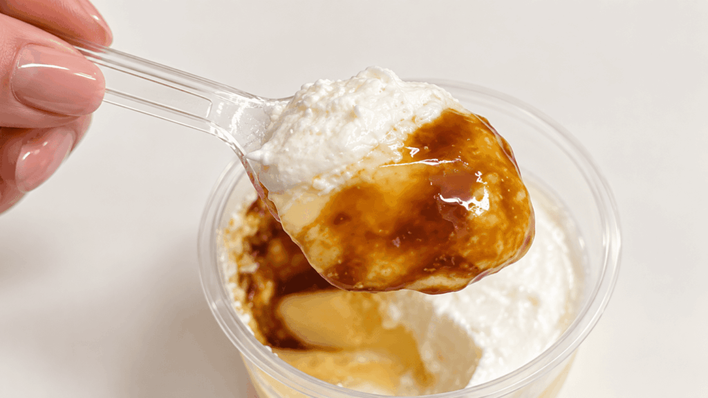 ファミマのクリームに溺れるとろけるプリンをホイップクリームとカラメルと一緒にスプーンですくった様子